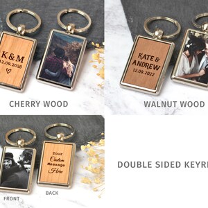 Puede incluir: Llaveros rectangulares de doble cara con marcos de metal plateado. Un lado presenta incrustaciones de madera con texto grabado como K&M 12.09.2020 o Kate & Andrew 12.09.2022, mientras que el otro lado muestra una fotograf&iacute;a impresa. Incluye anilla.