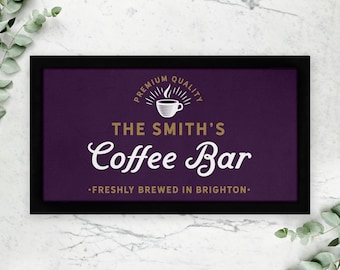 May include: A black framed sign with a purple background and gold lettering. The sign reads "Premium Quality" with a coffee cup icon, "The Smith's Coffee Bar", and "Freshly brewed in Brighton."