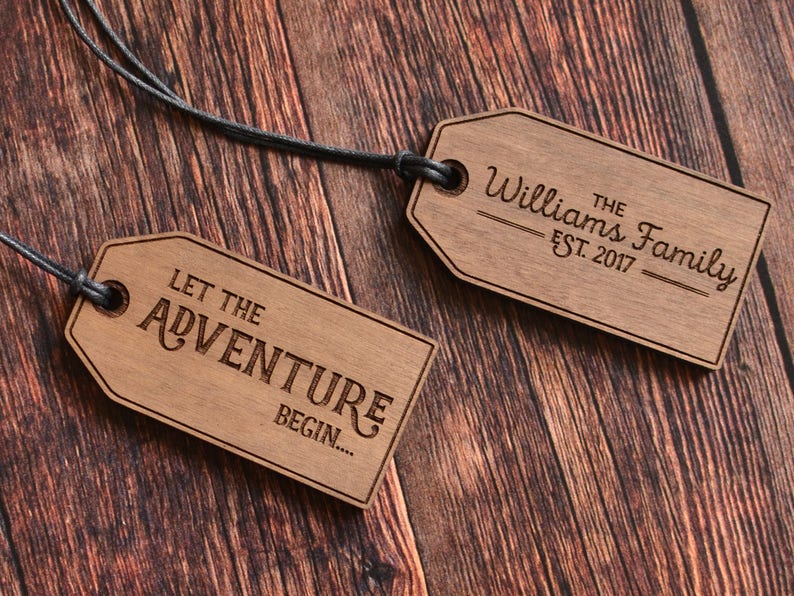 May include: Two wooden tags with black string. One tag says "Let the Adventure Begin..." and the other tag says "The Williams Family Est. 2017".