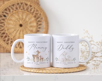 May include: Two white ceramic mugs with curved handles. One mug says "Happy Christmas Mummy" with a deer illustration, the other says "Happy Christmas Daddy" with a polar bear illustration. Both mugs have the text "Lots of Love, Freddie XX 2024".