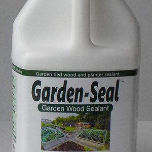 May include: A white plastic bottle of Garden-Seal garden wood sealant. The label includes the text "Garden-Seal" and "Non-Toxic". The product is designed for garden bed wood and planter sealant. The image shows a garden scene.