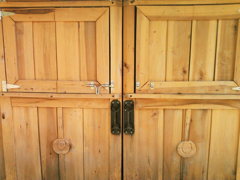 May include: Two wooden doors with black metal handles and a silver latch. The doors are made of horizontal planks and have a light brown color.