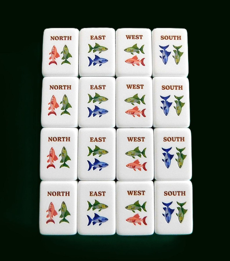 Peut inclure: Ensemble de tuiles de Mahjong blanches, chacune portant une direction cardinale : Nord, Est, Ouest et Sud. Chaque tuile pr&eacute;sente un motif de poissons color&eacute;s en rouge, vert, bleu et jaune.