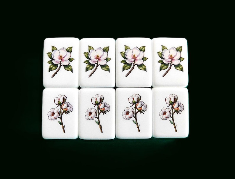 Peut inclure: Huit carreaux blancs avec des motifs floraux. La rang&eacute;e sup&eacute;rieure pr&eacute;sente des fleurs de magnolia avec des feuilles vertes, tandis que la rang&eacute;e inf&eacute;rieure affiche des brins de coton avec des boules blanches duveteuses. Les carreaux sont dispos&eacute;s sur un fond vert fonc&eacute;.