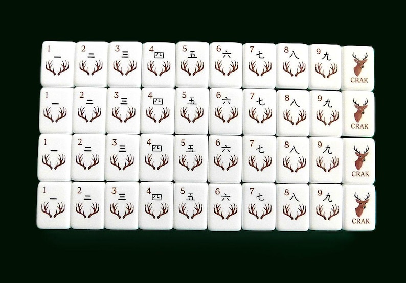 Peut inclure: Un ensemble de tuiles de Mahjong blanches avec des symboles et des chiffres bruns. Les tuiles pr&eacute;sentent des chiffres chinois et des motifs de bois de cerf. Le mot "CRAK" est imprim&eacute; sur certaines tuiles. Elles sont dispos&eacute;es sur un fond vert fonc&eacute;.