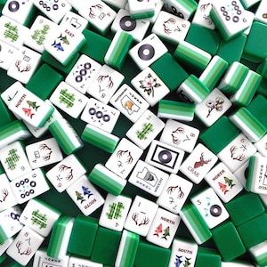 Peut inclure: Vue a&eacute;rienne d'une collection de tuiles de Mahjong blanches et vertes. Les tuiles pr&eacute;sentent divers symboles, chiffres et caract&egrave;res, notamment du bambou, des fleurs et des cerfs. Les tuiles vertes sont rectangulaires et entourent les tuiles blanches.