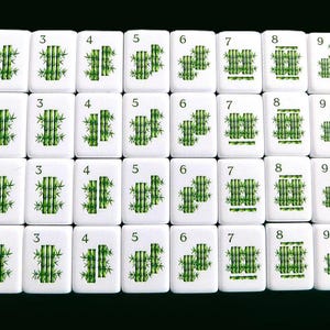 Peut inclure: Un ensemble de tuiles de Mahjong blanches avec des illustrations de bambou vert, d'oiseaux et de tracteurs. Les tuiles sont dispos&eacute;es en rang&eacute;es et en colonnes, affichant divers chiffres et symboles. Le mot "BAM" est imprim&eacute; sur certaines tuiles.