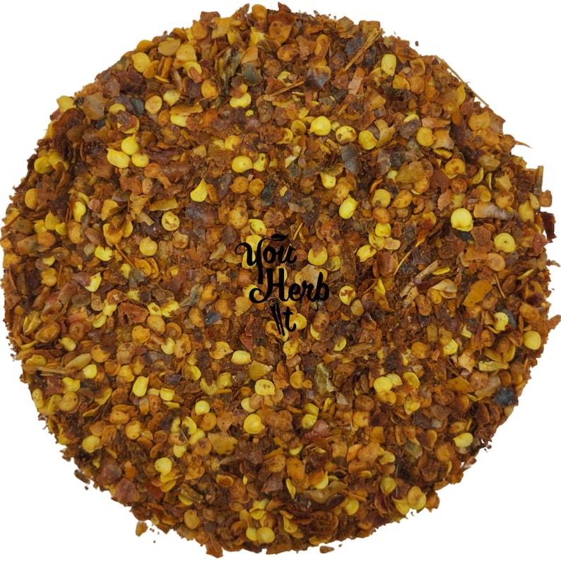 May include: Close-up of crushed red pepper flakes. The flakes are a mix of red, orange, and yellow. The flakes are small and irregular in shape.