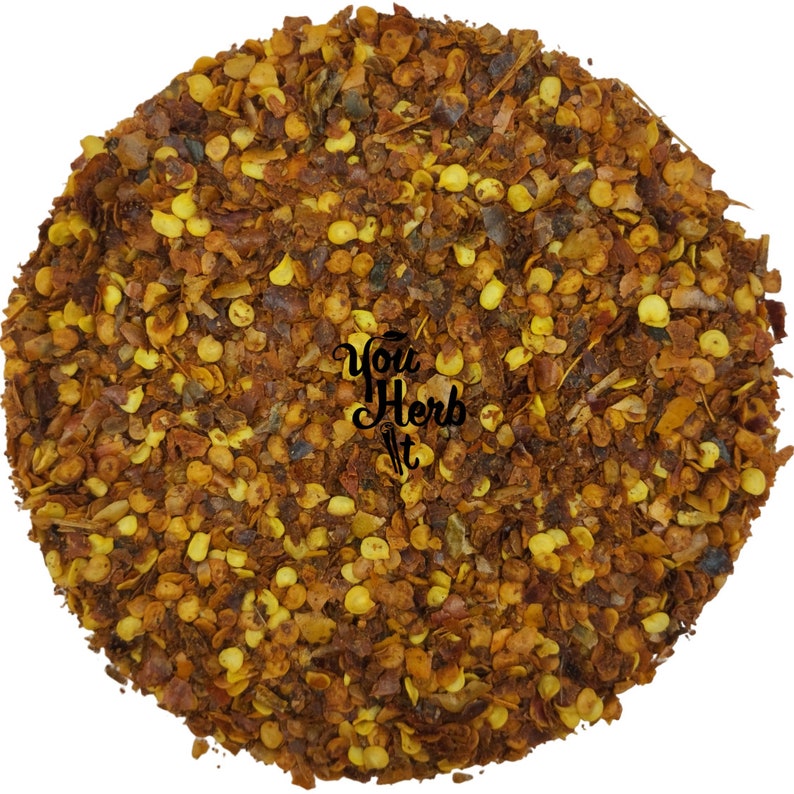 May include: Close-up of crushed red pepper flakes. The flakes are a mix of red, orange, and yellow. The flakes are small and irregular in shape.