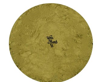 Puede incluir: Un recipiente circular lleno de un polvo fino de color verde claro. El texto "You Herb It" está impreso en escritura negra en el lado derecho del recipiente. El polvo tiene un aspecto ligeramente texturizado.