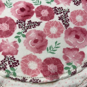 Puede incluir: Dos capas de tela con un patr&oacute;n floral rosa. La capa superior tiene un fondo blanco con flores rosas y hojas verdes. La capa inferior tiene un fondo blanco con peque&ntilde;os puntos rosas.
