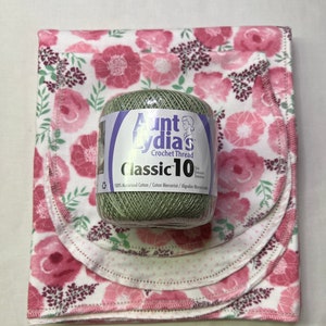 Puede incluir: Una bola de hilo de crochet Aunt Lydia's Classic 10 de color verde con texto blanco sobre un fondo de tela floral rosa y blanco.