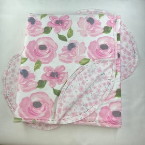May include: A pink and white baby blanket with a floral pattern. The blanket is made of soft, comfortable fabric and is perfect for cuddling.
