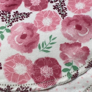Puede incluir: Una tela blanca con un patr&oacute;n floral rosa. La tela tiene un borde festoneado y est&aacute; doblada sobre s&iacute; misma.