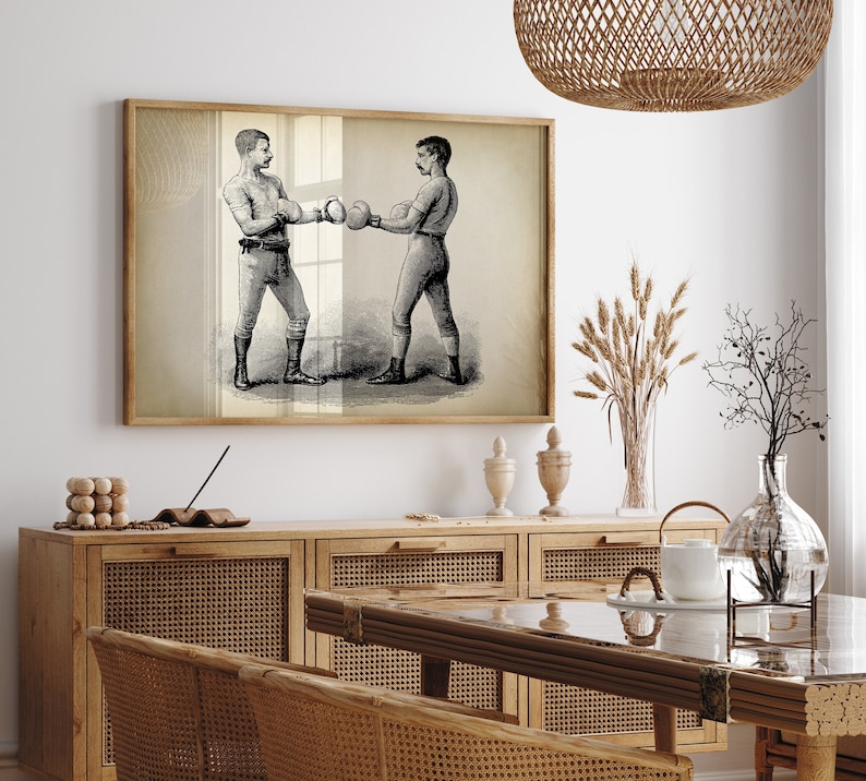 K&ouml;nnte beinhalten: Eine Vintage-Schwarzwei&szlig;illustration von zwei Boxern in einem Boxring. Das Bild ist gerahmt und h&auml;ngt an einer Wand &uuml;ber einem Holzschrank.