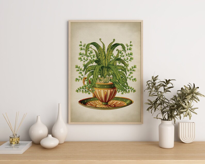 May include: A vintage botanical illustration of a fern plant growing in a teacup and saucer. The teacup is decorated with green and gold accents. The illustration is framed in a light wood frame.
