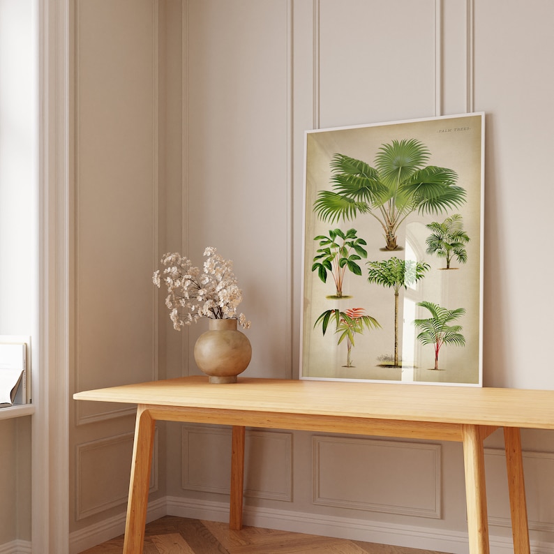 Puede incluir: Una ilustraci&oacute;n bot&aacute;nica enmarcada de varias palmeras, con el t&iacute;tulo "Palm Trees" en la parte superior de la impresi&oacute;n. La impresi&oacute;n est&aacute; colgada en una pared blanca sobre una mesa de madera.