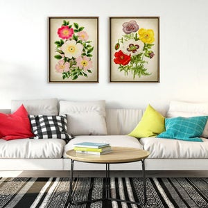May include: Two framed floral prints with white, pink, red, and yellow flowers on a white background. The prints are hanging on a white wall above a white couch with colorful throw pillows.