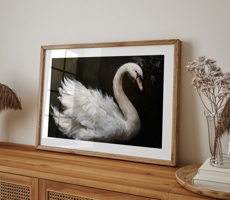 May include: A framed print of a white swan with its head turned to the side, set against a dark background. The swan's feathers are detailed and the image has a painterly style.
