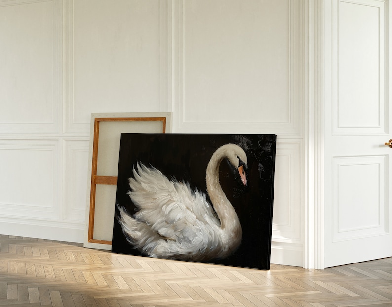May include: A white swan with its head turned to the side, painted on a black canvas. The swan is in a graceful pose with its wings spread out. The painting is framed and leaning against a white wall.