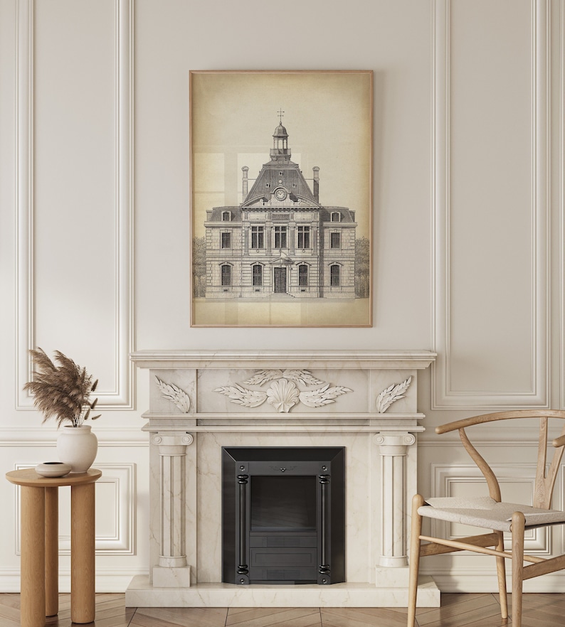 Op de afbeelding: Een zwart-witte tekening van een gebouw met een klokkentoren, ingelijst in een licht houten lijst, hangt boven een witte marmeren open haard met een zwarte haard inzet. De open haard bevindt zich in een kamer met witte muren en lambrisering.