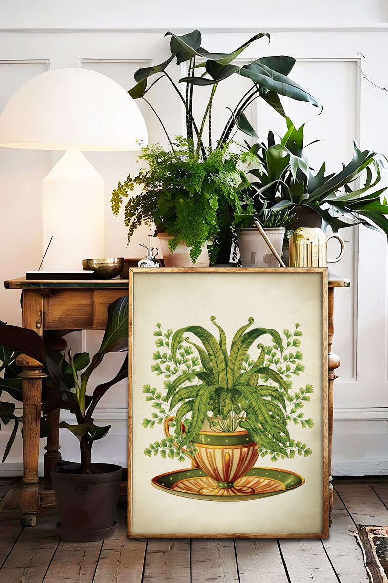 May include: A framed botanical illustration of a fern plant growing in a vintage teacup and saucer. The teacup is decorated with green, orange, and yellow stripes and a white polka dot pattern. The saucer is green with a yellow and orange stripe pattern.