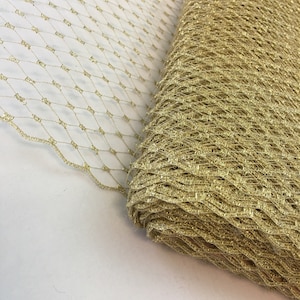 May include: Gold glitter mesh fabric. The mesh is a diamond pattern. The fabric is rolled up.