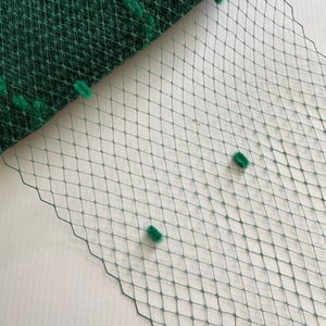 May include: Green tulle fabric with a diamond pattern and small green pom-poms.