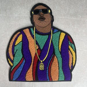 Può includere: Toppa ricamata di un rapper con occhiali da sole e una camicia con un motivo colorato con una catena d'oro e un ciondolo.