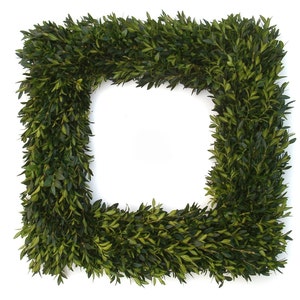 May include: A square frame made of green boxwood greenery. The frame is perfect for a wreath or other decorative purposes.