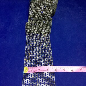 May include: A roll of clear rhinestone trim with a geometric pattern. The trim is approximately 6 inches long and is measured with a pink tape measure.