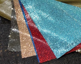 Op de afbeelding: Vijf verschillende kleuren strass-mesh stof. De kleuren zijn zwart, zilver, goud, rood en blauw.
