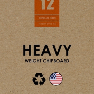 May include: A brown cardboard sheet with the text "Studio 12" in a red rectangle. The text "Chipboard Sheets" and "Product of the USA" are also printed on the sheet. The text "Heavy Weight Chipboard" is printed in black. A black recycling symbol and a red, white, and blue American flag are printed below the text. The text "Design Ideation Studio" is printed in black with a stylized "j" logo.