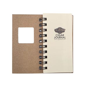 May include: A spiral-bound journal with a brown kraft paper cover featuring a square cutout. The cream-colored title page displays the black text CIGAR PROP CIGAR JOURNAL and the website www.cigarprop.com, held together by a black metal wire coil.