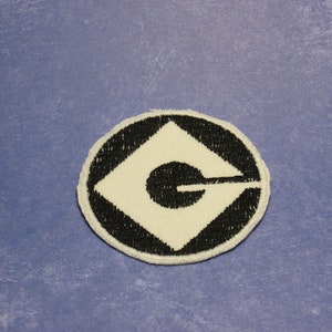 May include: A black and white embroidered patch with the iconic Minion logo, a white G inside a black diamond shape, surrounded by a black circle.