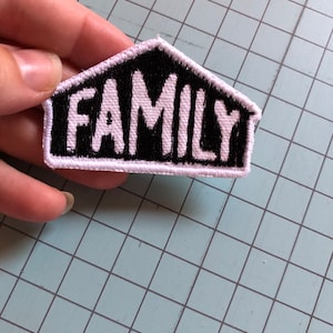 Puede incluir: Parche bordado blanco con forma de casa negra y la palabra "FAMILY" en letras blancas.