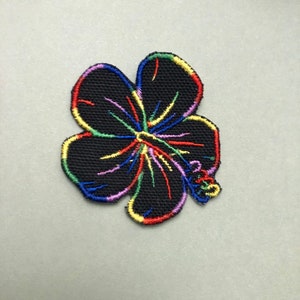 May include: Black embroidered hibiscus flower patch with rainbow-colored accents. The flower's petals are outlined in a vibrant array of colors, with a detailed center. This patch is suitable for clothing, bags, or other fabric items.