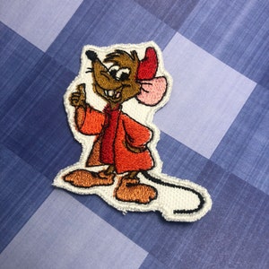 Puede incluir: Parche bordado de un ratón de dibujos animados con un abrigo y un sombrero rojos, haciendo un pulgar hacia arriba.