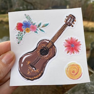 May include: A set of four stickers featuring a brown acoustic guitar, a pink flower, a yellow swirl, and a cluster of colorful flowers.