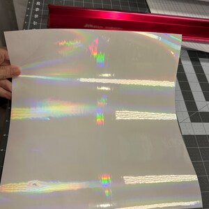 May include: A sheet of iridescent vinyl with a rainbow holographic finish. The vinyl is white with a subtle shimmer.