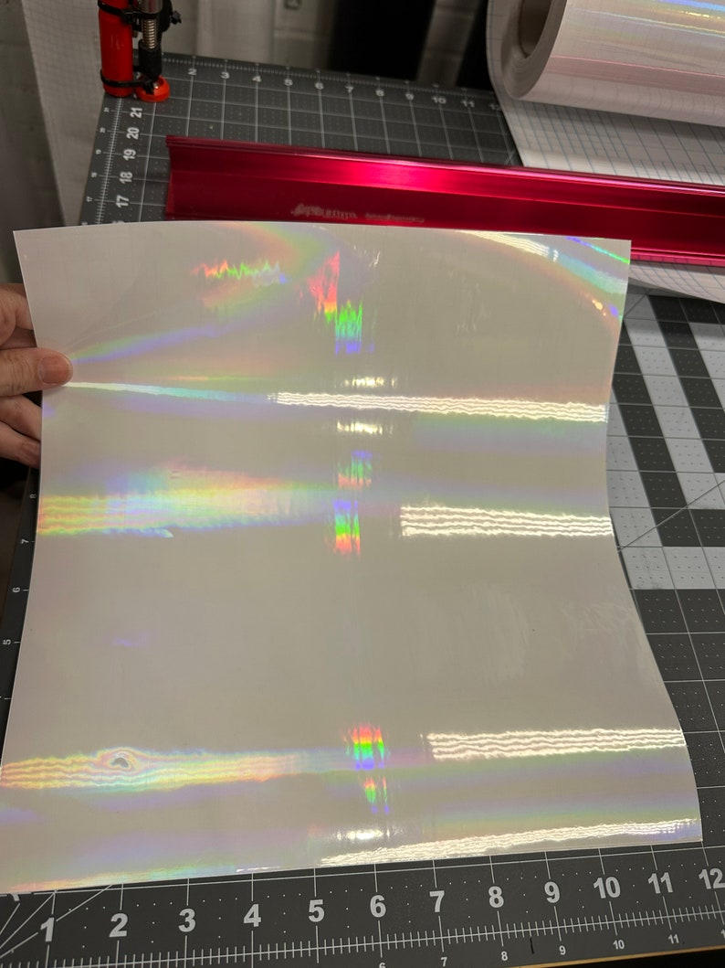 May include: A sheet of iridescent vinyl with a rainbow holographic finish. The vinyl is white with a subtle shimmer.