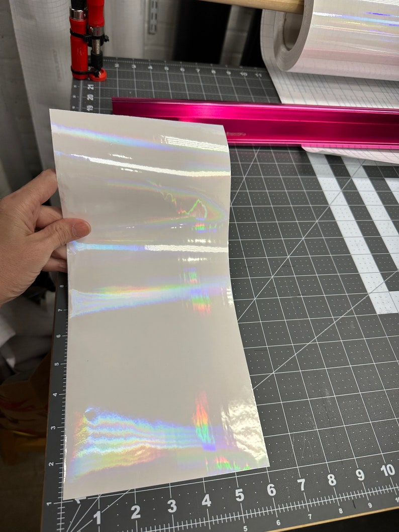 May include: A sheet of iridescent vinyl with a rainbow sheen. The vinyl is white with a holographic finish.