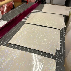 May include: Four sheets of iridescent white vinyl with a holographic finish. The vinyl is cut to size and ready to be used for crafting projects.