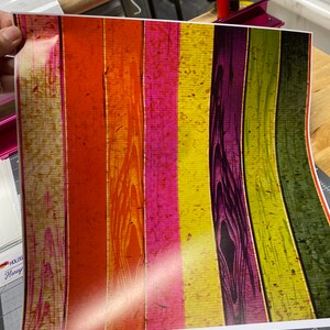 May include: A colorful woodgrain patterned vinyl sheet with vertical stripes in shades of yellow, orange, red, pink, purple, and green. The vinyl sheet is designed to be used for crafting and DIY projects.