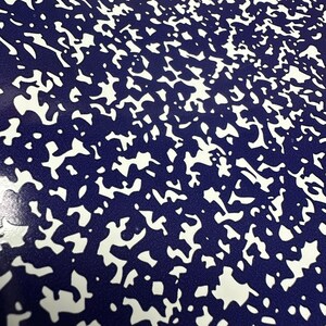 May include: A close-up of a blue and white speckled surface. The surface has a random pattern of white spots on a dark blue background.