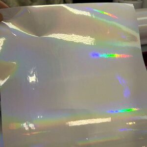 May include: A sheet of iridescent white vinyl with a rainbow holographic effect. The vinyl is smooth and glossy.