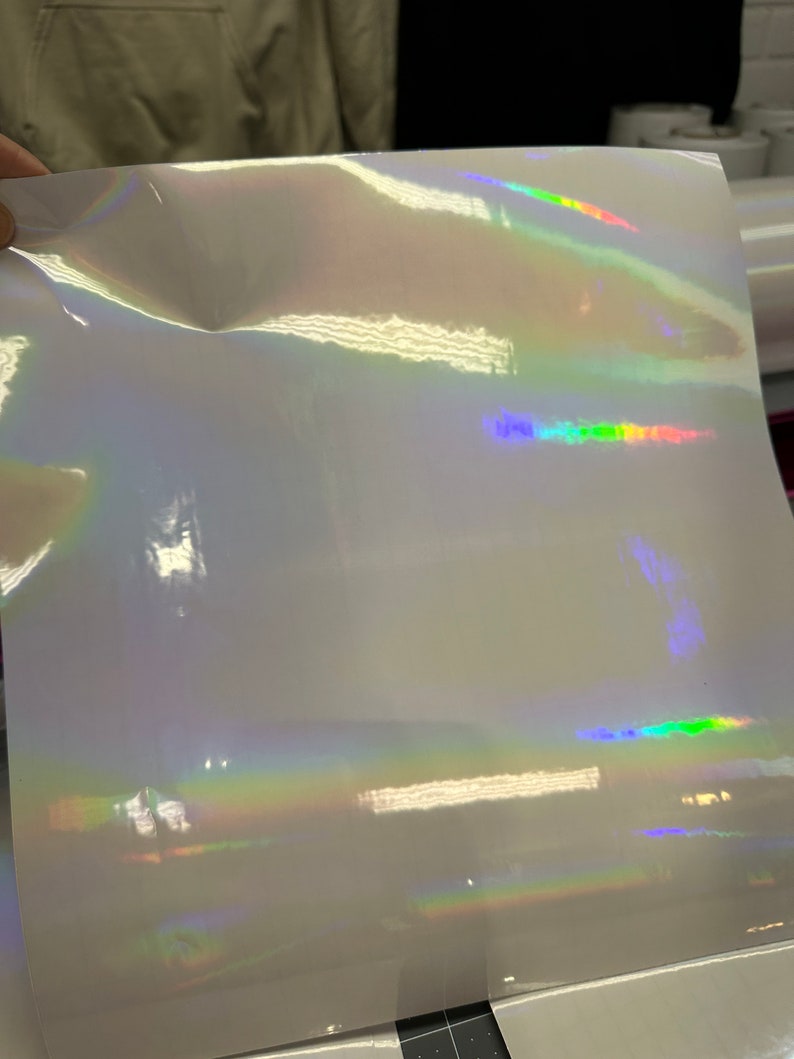 May include: A sheet of iridescent white vinyl with a rainbow holographic effect. The vinyl is smooth and glossy.