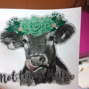 May include: A black and white cow with a green glitter flower crown, with the text "not today, heifer" written below.