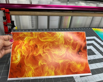 May include: A close-up of a printed sheet of orange, yellow, and red flames. The sheet is being held by a hand.