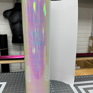 May include: A roll of iridescent vinyl with a white backing paper. The vinyl has a pearlescent finish with a rainbow of colors.